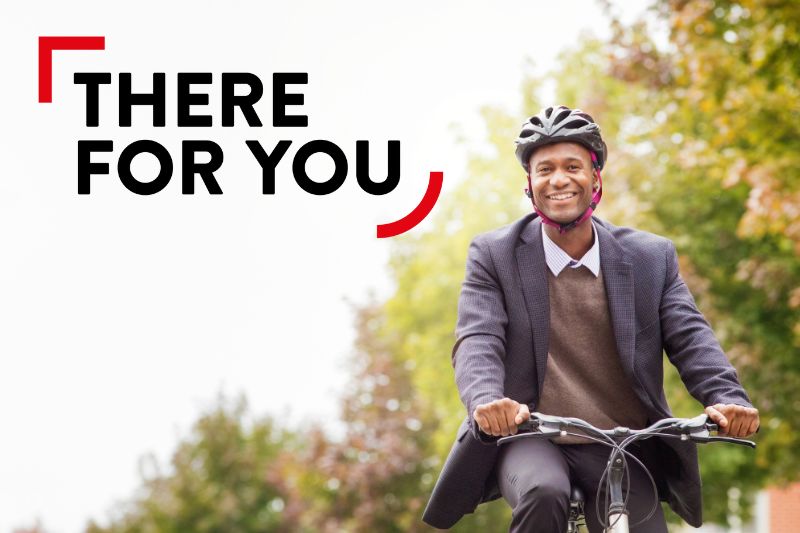 MAN IN BUSINESS WEAR CYCLING WITH TREES BEHIND HIM